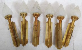 A set of 6 brass plated wall mounted olympic flame uplighters complete with 6 frosted glass shades
