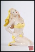 A Bisqueware figure in Art Deco style of a kneeled woman with yellow clothing. 15cm tall.