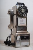 A reproduction novelty American telephone in the style of a payphone. 45cm tall.