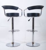 A brand new un-used pair of contemporary black leather gas operated bar stools having foot rest
