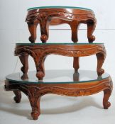 A nest of 3 Chinese style hardwood and glass graduating tables. The carved legs with oval frames