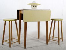 A 1960's yellow Formica drop leaf table along with two matching stools and a retro 1960's yellow