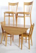 A large formica drop leaf dining table having inverse tapering beech legs with a faux wood formica