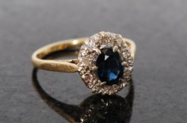 An 18ct gold sapphire and diamond ring. The central blue sapphire being surrounded by a cluster