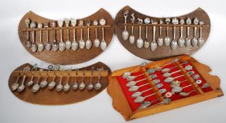 A collection of souvenir spoons on decorative hanging wooden plaques. Some UK, some Continental