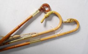 Three walking canes decorated with glass-eyed swan heads.