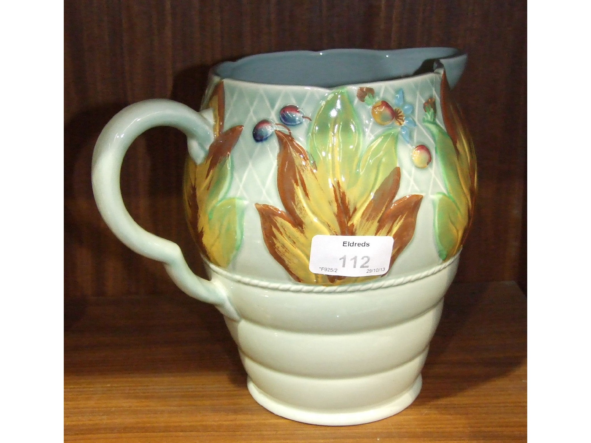 A Clarice Cliff green-glazed jug with raised autumn leaves and berries decoration, 18cm high,