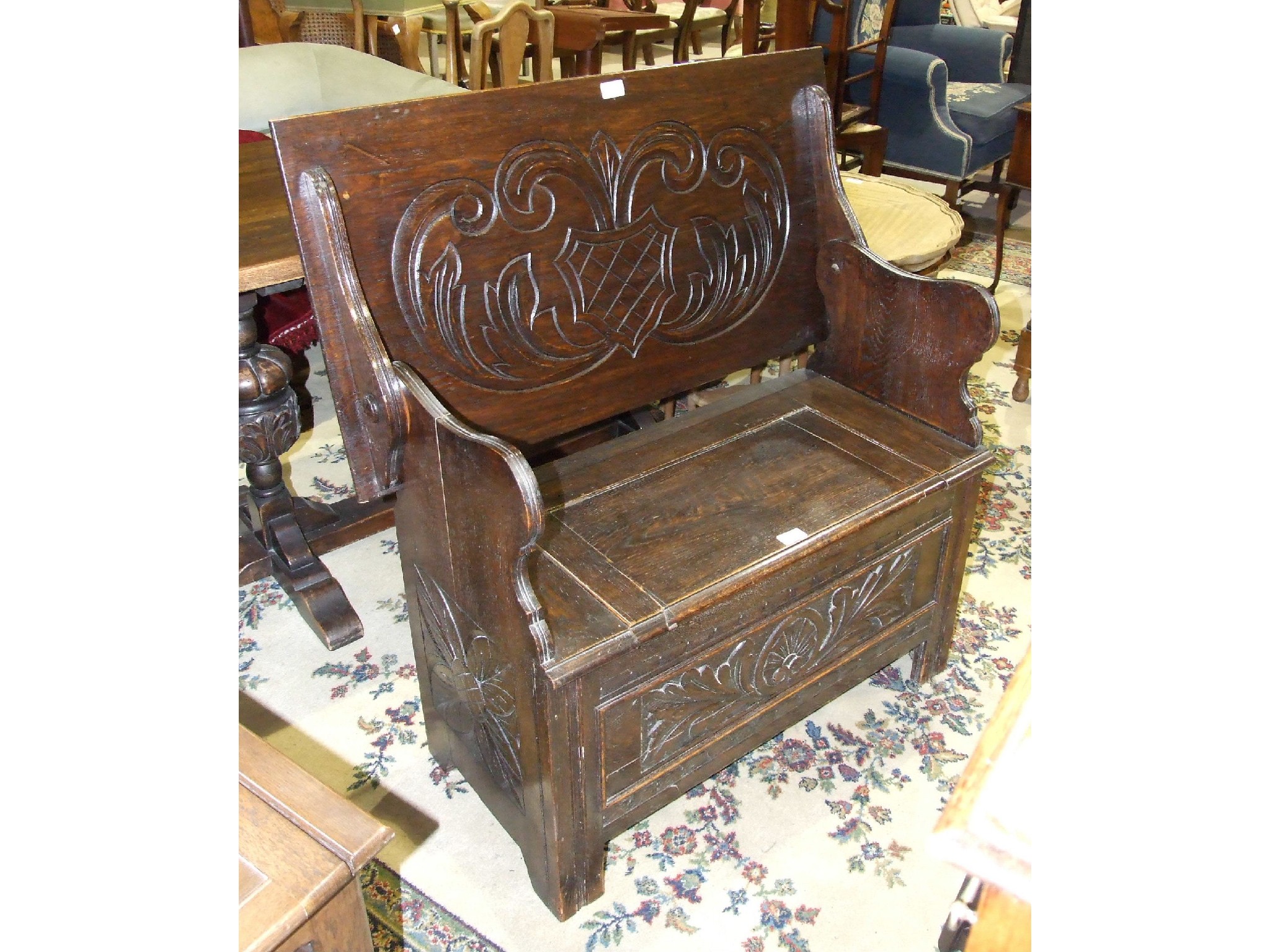 A 20th century oak monks bench with carved back and lift seat, 92cm.