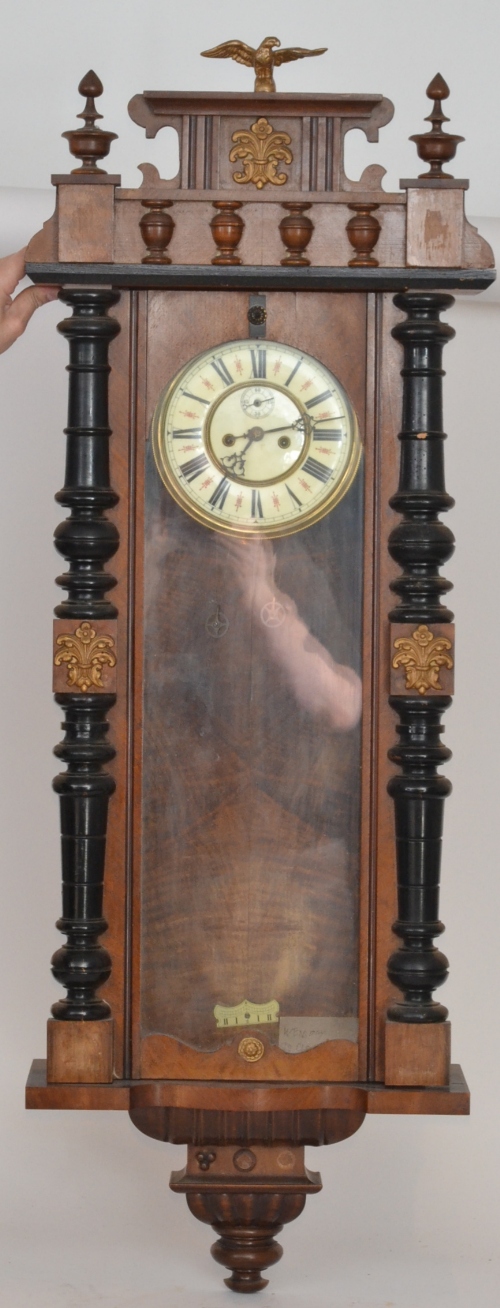 An early 20th Century walnut cased Vienna wall clock with a moulded cornice pediment above the