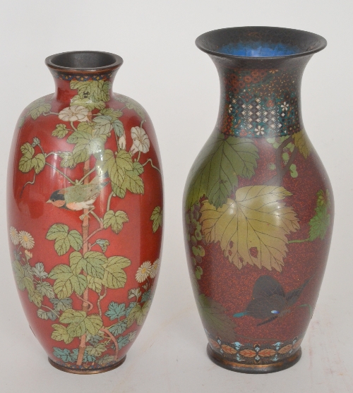 An early 20th Century cloisonne baluster vase decorated with butterflies and fruiting vines on a red