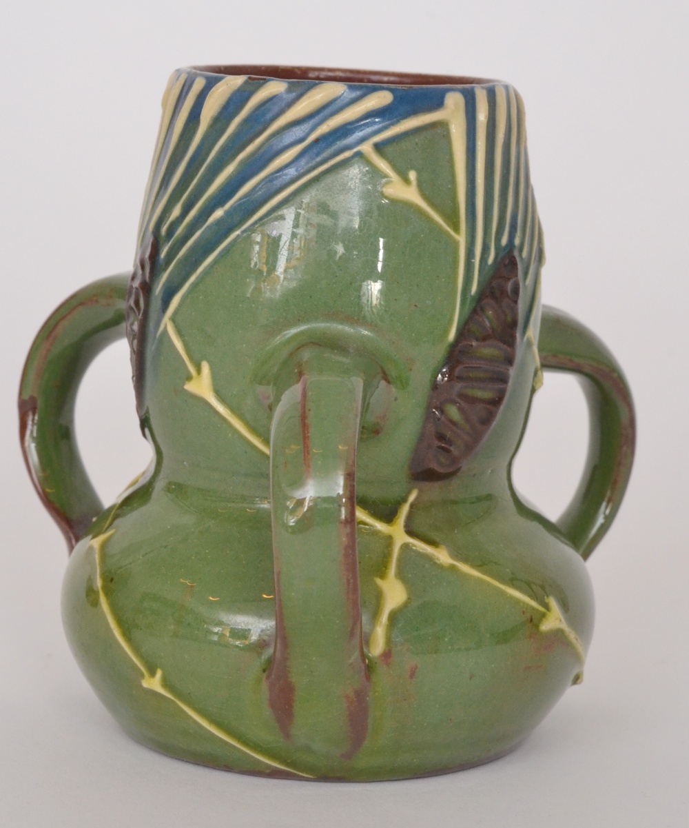 An early 20th Century C.H Brannam Barum pottery tri-handled posy vase decorated in a green slip with