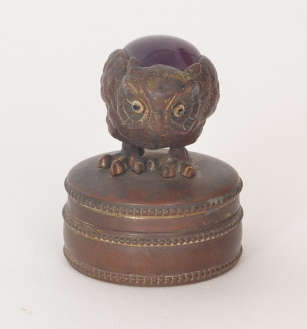 A late 19th Century circular bronze jewellery case, plush lined, mounted with a crouched owl with