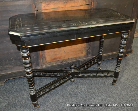 A late 19th Century Aesthetic Movement ebonised fold-over card table raised to a turned bobbin cross