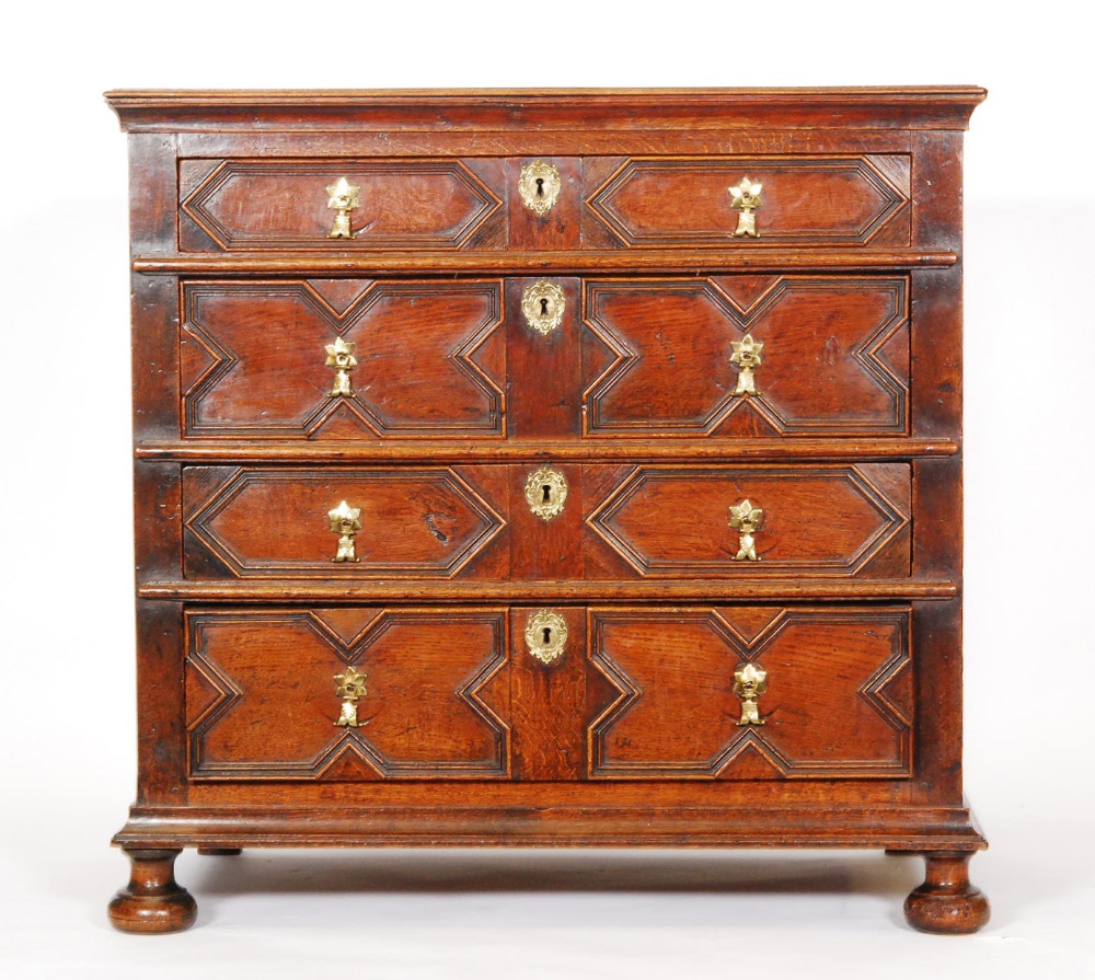 An 18th Century oak geometric moulded front chest of four long graduated drawers, brass drop