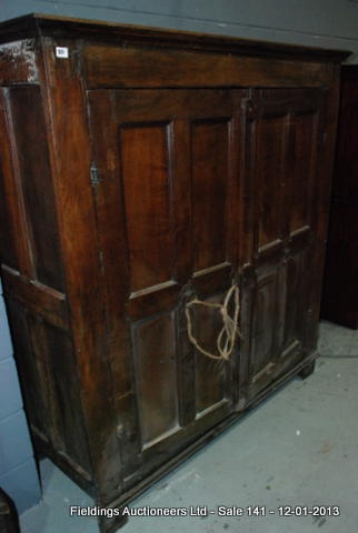 An 18th Century oak and fruitwood press cupboard, enclosed by a pair of twin panelled doors below