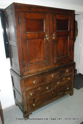 An oak press cupboard on chest, with double doors over three dummy frieze drawers and a further