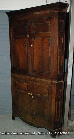 An oak freestanding corner cupboard with mahogany cross-banded detail above bracket feet, 117cm wide