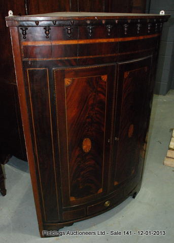 A large Georgian mahogany bow-fronted wall hanging corner cupboard with an inlaid oval cartouche and