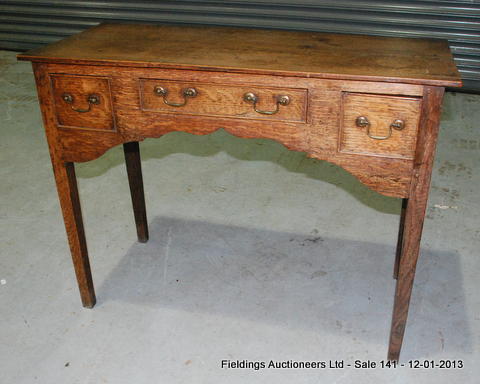 A George III oak lowboy, fitted with three short drawers, brass swan neck handles, on square