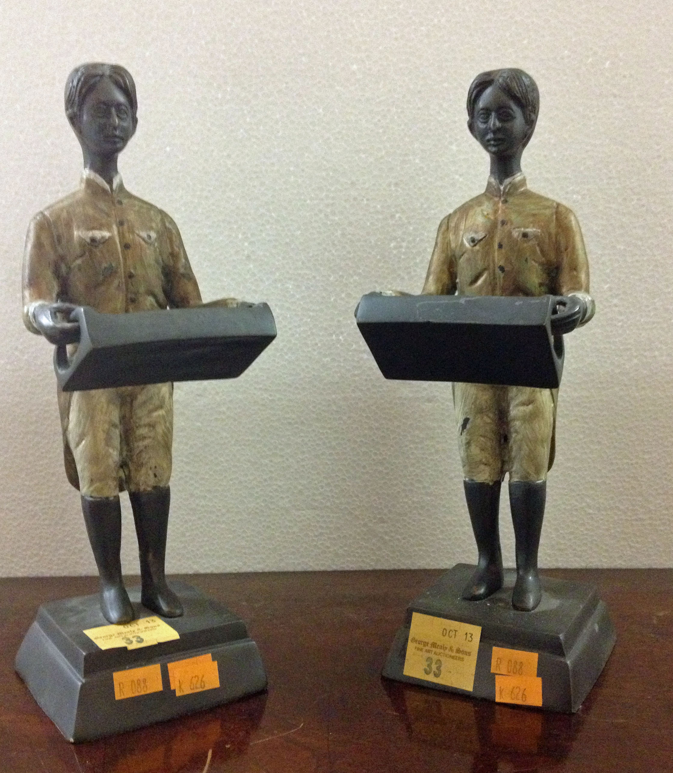 A pair of painted bronze Figures, of two Servants each holding a tray, 26cms (10 1/4") high, 20th