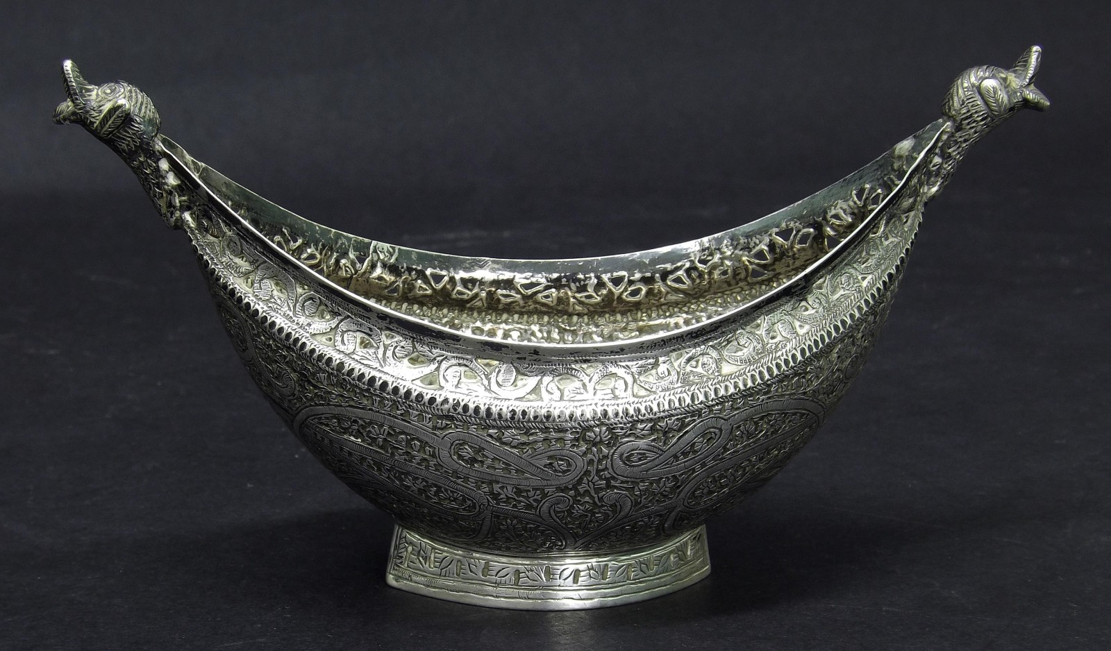 Eastern white metal quaich with moulded duck head handles and engraved with scrolling foliage, 6"