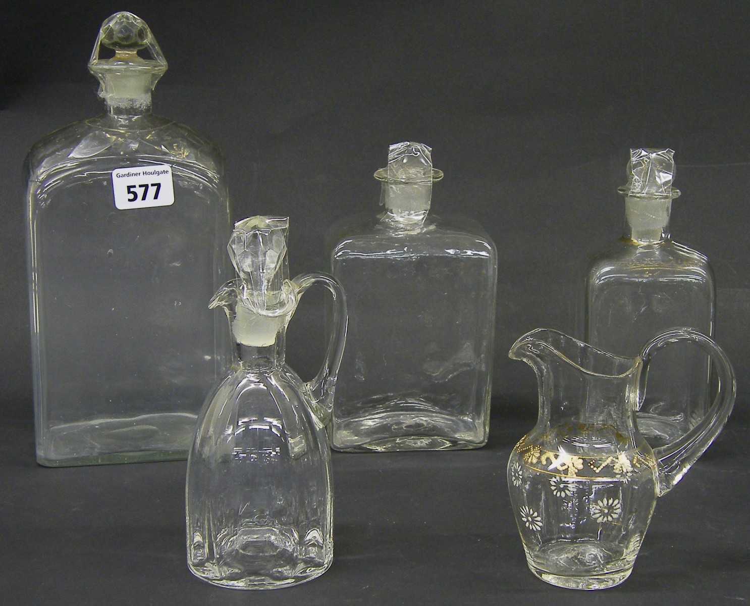 Three antique square glass decanters, with faded gilded overlay; together with a further glass jug