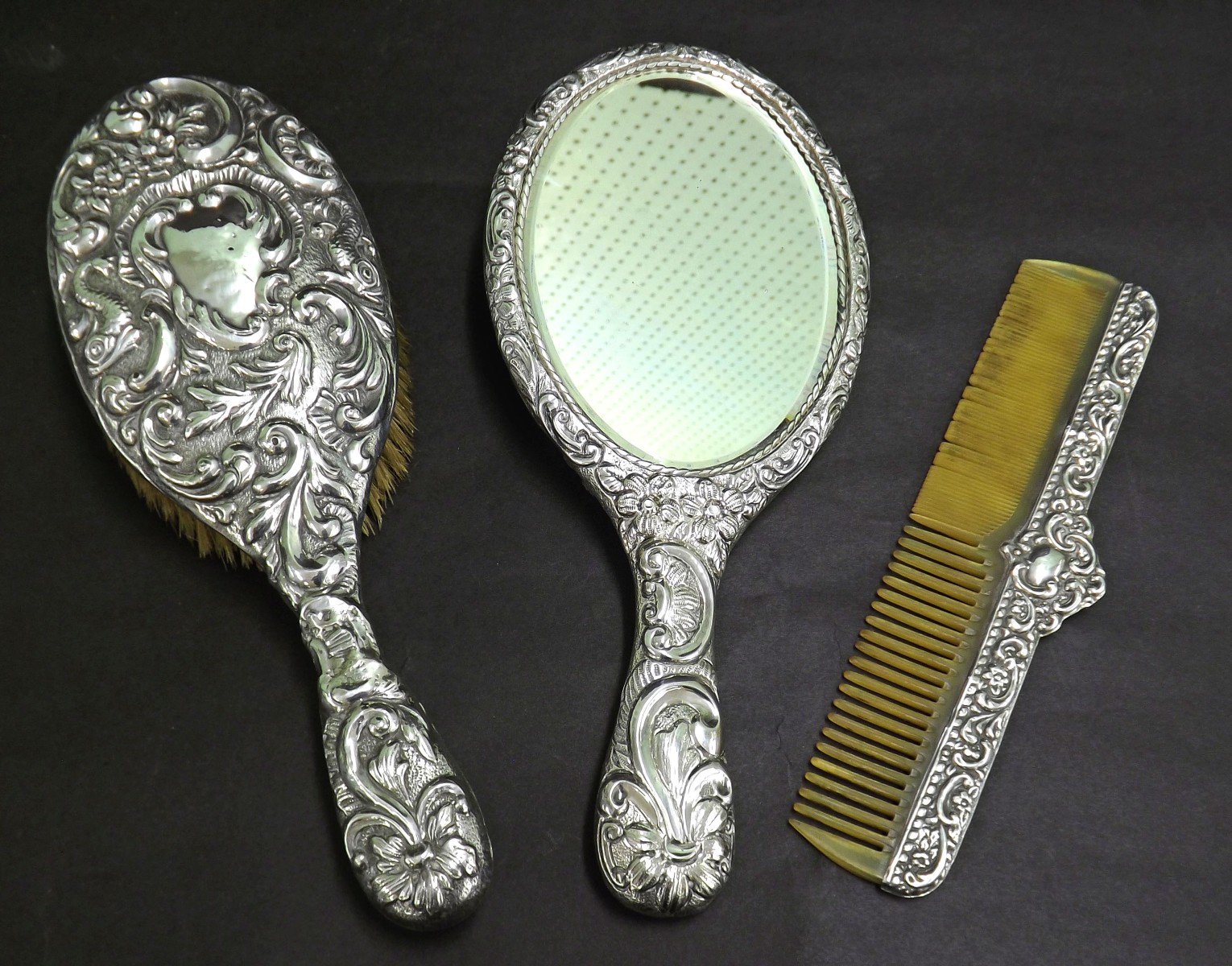 Edwardian three piece dressing set, comprising mirror, brush and comb, all embossed with scrolling