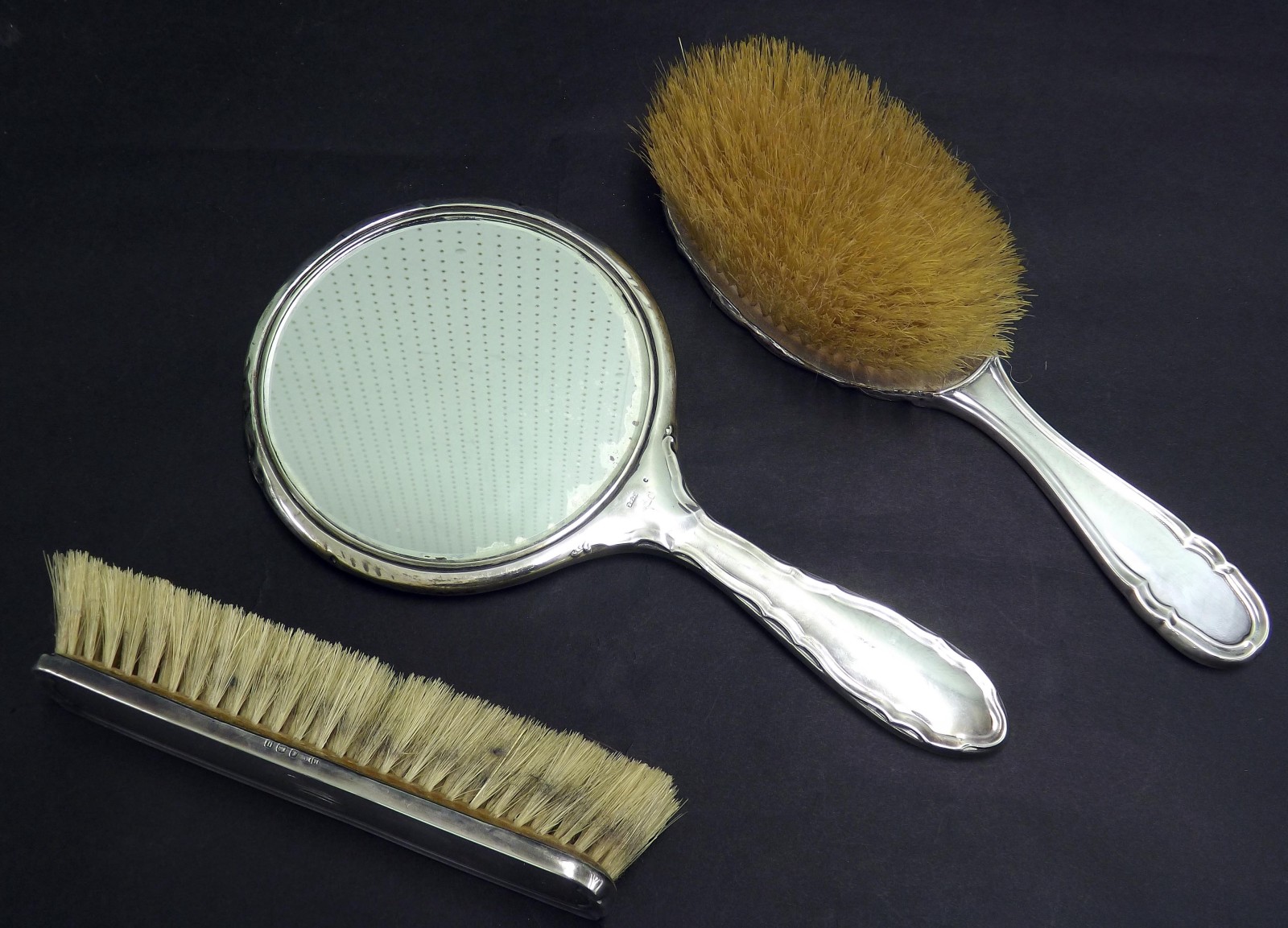 George V silver three piece dressing set, comprising mirror and two brushes with scallop rim,