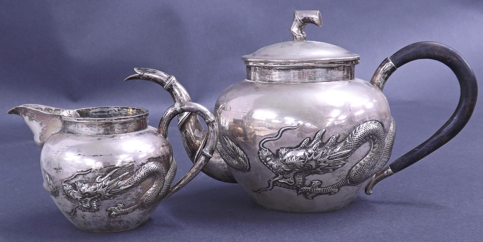 Chinese silver part tea service comprising teapot and milk jug, each embossed with a dragon band and