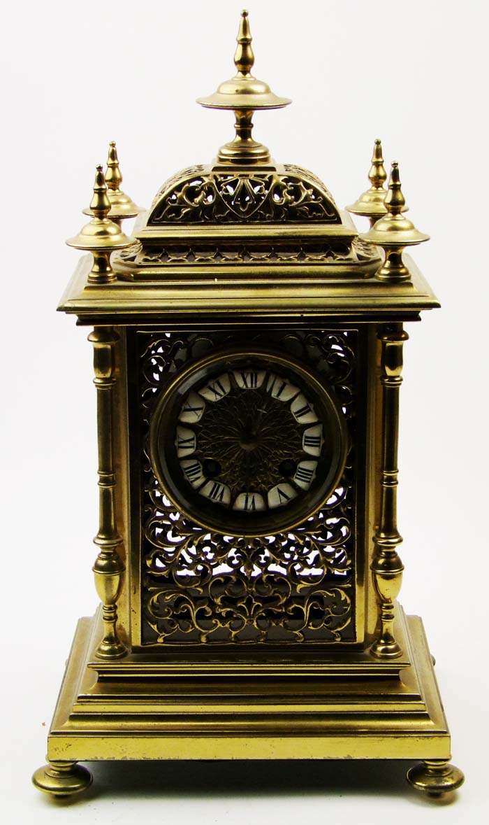 A pierced brass mantel clock, the dial with enamel roman numerals, the movement striking on a