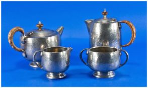 A Planished Pewter Four Piece Tudric Tea Set consisting of a tea pot, hot water jug both with