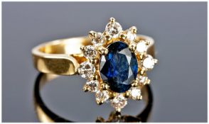 18ct Gold Diamond And Sapphire Cluster Ring Set With A Central Oval Sapphire Surrounded By 12 Round