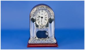 An Italian Silver Faced Pendulum Mantle Clock. Decorated with embossed foliate panels. Oval Roman