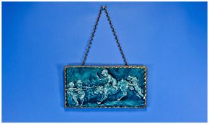 Framed Staffordshire Tile depicting putti with a dog. In brass frame. 12 by 6 inches.