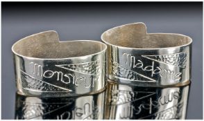 A Stylish Pair of French Art Deco Oval White Metal Napkin Rings. One designed as ``Monsieur``, the