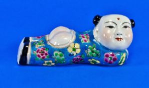 A Small Chinese Sleeping Figure Depicting A Smiling Child. Out stretched in coloured blue robes,
