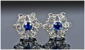 18ct White Gold Diamond And Sapphire Earrings, Set With A Central Round Sapphire Surrounded By Six