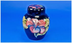 Moorcroft Lidded Ginger Jar. `Hibiscus` pattern in various colours on blue ground. Labels to lid