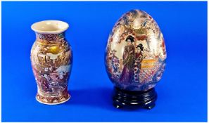 A Satsuma Decorated Egg on a wooden base, together with small Satsuma vase, decorated with children