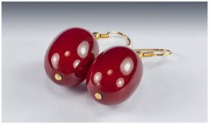 Pair of Dark Cherry Red Amber Earrings, each oval opaque amber drop just under 1 inch long, with