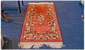 Small Woolen Symmetrical Patterned Floral Rug, on a red ground, measuring 64 by 27 inches.