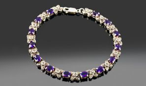 Silver Bracelet Set With 14 Oval Amethysts Between Marcasite Flower Head Links, Length 8 Inches.