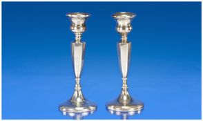 A Silver Pair Of Candlesticks with tapered and faceted stems supported on a circular stepped base.