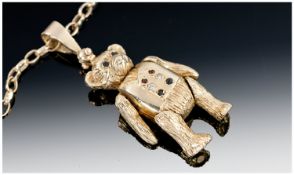 A 9ct Gold Reticulated Teddy Bear Pendant supported on a 9ct gold chain. The waistcoat set with