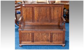 Early 20th Century Oak Box Settle, fitted with candle support, large wide arms to sides, the lid