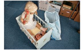 Painted Wooden Dolls Cot, containing a collection of various dolls and clothing.