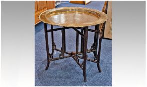 Brass Topped Chinese Circular Table, the base with a folding stand, the top engraved with foliage