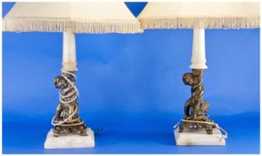 Pair of Modern Gilt Figural Table Lamps, each with a cream shade with fringed edge, raised on a