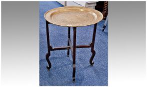 Brass Topped Coffee Table, raised on gate-leg action, with circular engraved top, measuring 23