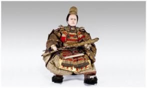 A Fine Quality Meji Period Samuri Seated Figure, dressed in fine gold embroidery, and wearing